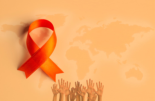 Orange awareness ribbon and hands on orange background.