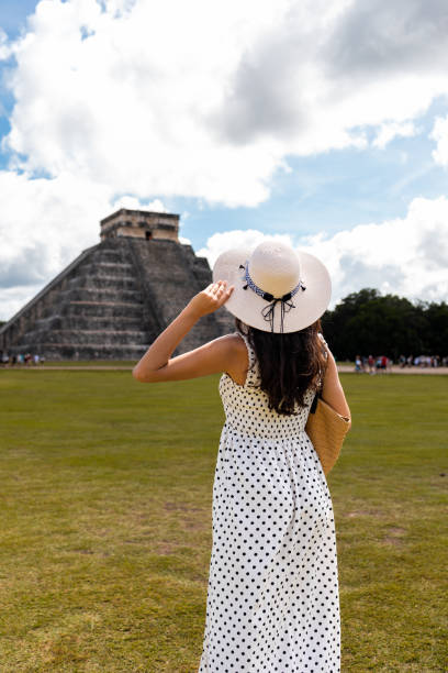 Latin tourist visiting Chichen Itza pyramid in Mexico. She is enjoying beautiful view