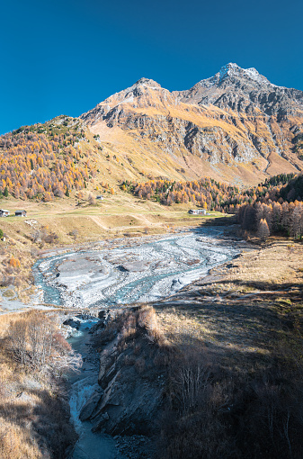 Orlegna River in Maloja region, Switzerland on a sunny day in October. In the background the mountain peaks \