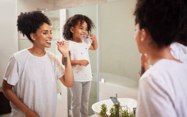 istock Mirror reflection of mom and girl brushing teeth together while bonding, having fun and enjoy quality time. Child development, learning or dental care for oral hygiene girl cleaning teeth in bathroom 1446069968