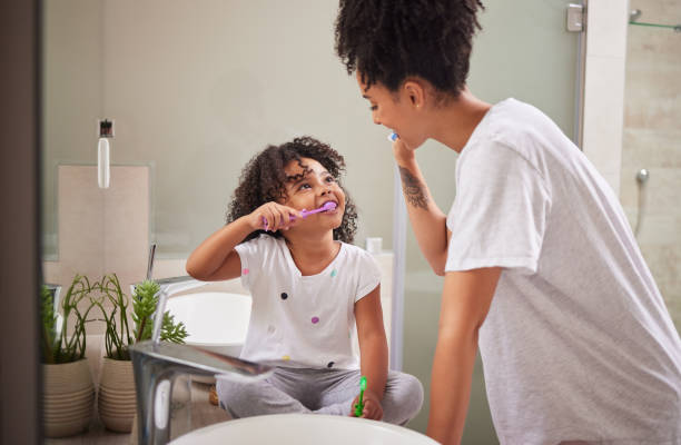 family morning, dental cleaning and mother teaching child to brush teeth in bathroom, care for mouth health and smile for healthcare with toothbrush. girl happy learning about dentistry with mom - offspring child toothy smile beautiful imagens e fotografias de stock