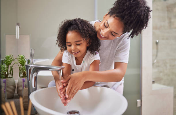 family, washing hands and child with mom rinsing, cleaning and good hygiene against bacteria or germs for infection or virus protection in bathroom. girl kid with woman for health and cleanliness - washing hands imagens e fotografias de stock