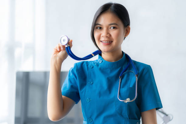 白い背景に聴診器と青衣を着たアジアの女性看護師、医療コンセプト - lab coat nurse doctor female doctor ストックフォトと画像