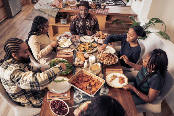 Black Thanksgiving A Black family gathers together to cook and eat a Thanksgiving meal. family dinners and cooking stock pictures, royalty-free photos & images