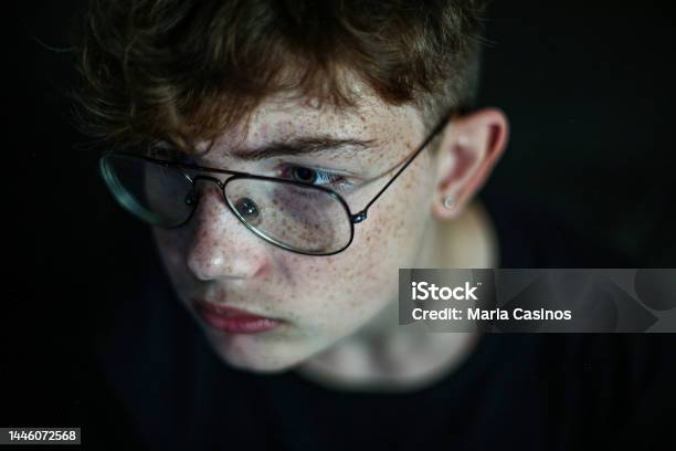 Closeup Of Teenager Boy Redhead With Freckles And Glasses On Black Background Stock Photo - Download Image Now