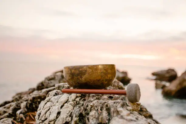 Golden singing bowl stands on a stone - closeup
