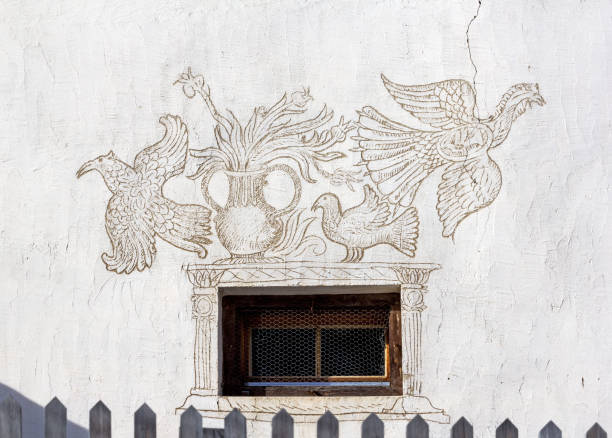 Ardez, Switzerland - January 27. 2022: Traditional house facade with faune figure by Sgraffito technique in Grisons regions, Switzerland. Sgraffito technique applies layers of plaster tinted in contrasting colours to a moistened surface.