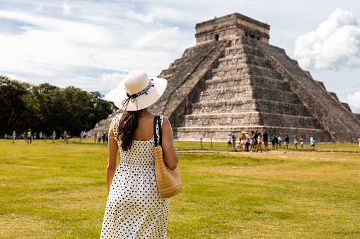 Latin woman visiting Chichen Itza pyramid in Mexico. She is enjoying beautiful view