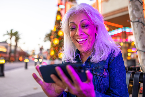 An adult playing games on phone at twilight with neon lighting