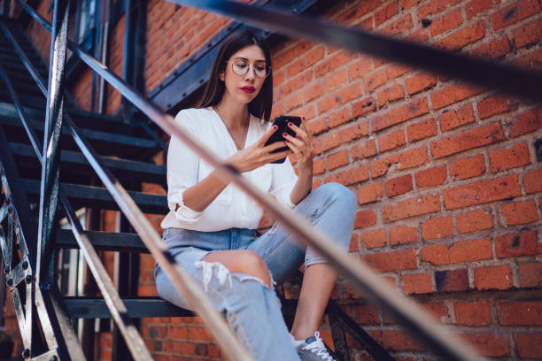istock Smart young female texting on cellphone on stairs 1446075597
