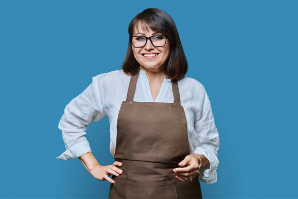 istock Confident middle aged woman in apron looking at camera on white background 1446075791