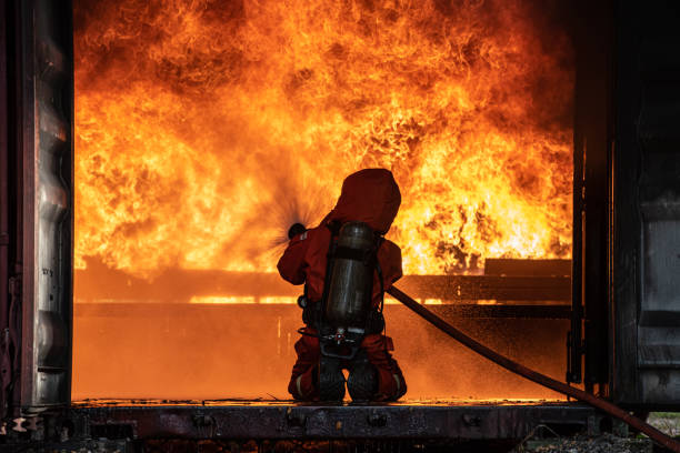 istock Firefighter Rescue training to stop burning flame, Fireman wear hard hat and safety uniform suit for protection burn using hose with chemical water foam spray. 1446077357