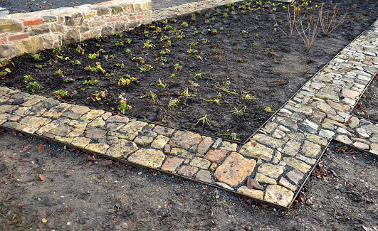 stone pavement just laid dry in the gravel backfill between two sheet steel curbs. sandstone and pieces of burnt brick with a rustic feel. narrow park paths in the herb garden, soil, cultivation, dry wall, layer, geotextile, classify, categorize, perennial garden, workspace