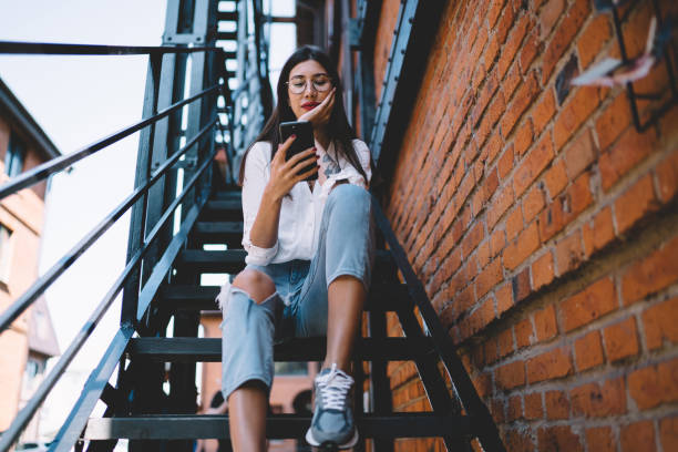 istock Young smiling lady texting on cellphone in city 1446077982