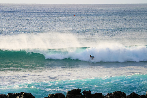 A Man Surfing on the Huge Waves in Pacific Ocean at Hanga Roa Town, Easter Island, Chile, South America