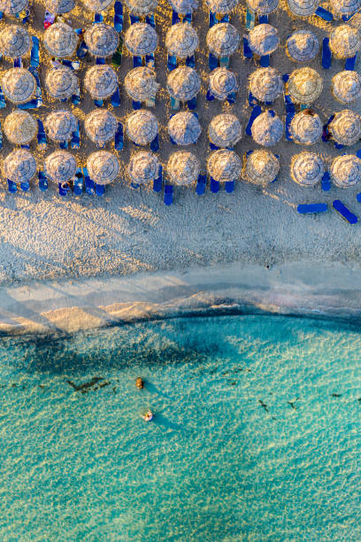 Aerial view of sandy beach with colorful umbrellas, swimming people in sea bay with transparent blue water at sunset in summer. Aerial top view on the beach, umbrellas, sand and sea waves. Aerial view of sandy beach with colorful umbrellas, swimming people in sea bay with transparent blue water at sunset in summer. Aerial top view on the beach, umbrellas, sand and sea waves. costa esmeralda stock pictures, royalty-free photos & images