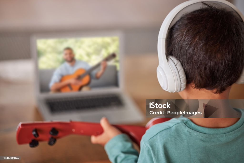Education, laptop and child with guitar learning how to play on remote lesson, e learning or streaming tutorial video. Talent, online musician course or creative kid study music with teacher or coach 20-24 Years Stock Photo