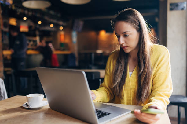 istock A woman works remotely using a laptop while sitting in a coffee shop drinking coffee 1446083061