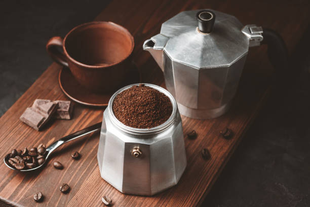 Moka coffee pot filled with brown ground coffee on dark wooden board, prepare to brewing Italian espresso Moka coffee pot filled with brown ground coffee on dark wooden board, prepare to brewing Italian espresso. moka stock pictures, royalty-free photos & images