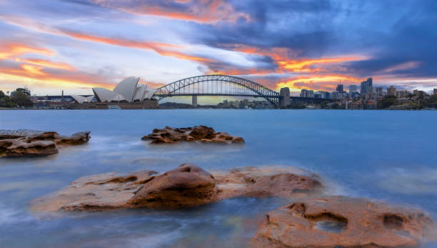 Sydney Harbour Australia at Sunset with the turquoise colours of the bay and high rise offices of the City in the background Sydney Harbour Australia at Sunset with the turquoise colours of the bay and high rise offices of the City in the background sydney skyline sunset stock pictures, royalty-free photos & images