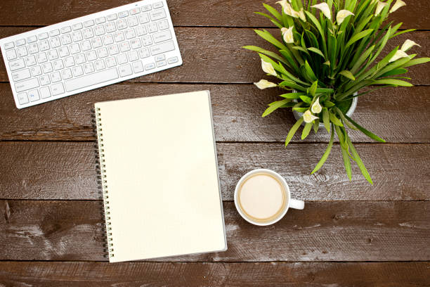 flat lay desktop, Modern computer keyboard, lilies flower's pot and cup  coffee milk  with notebook. on wood table