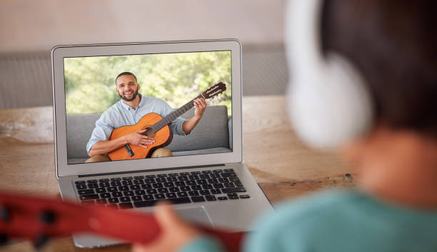 istock Learning guitar, video call and instructor teaching a girl an instrument, live streaming class and communication on virtual broadcast on internet. Student musician learning to play with tutor on web 1446083975