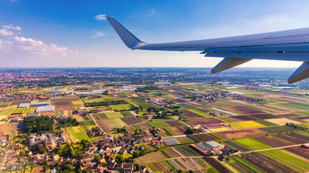 istock Airplane windows view above the earth on landmark down. View from an airplane window over a wing flying high above farmlands and fields. View from window of plane airplane flying. 1446084346