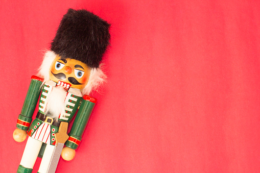Interesting beautiful christmas nutcracker soldier on red colored paper surface texture with copy space