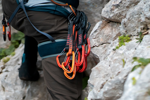 A man with climbing equipment, with easy-clipping carabiners and quick draws, hiker stands against the background of mountains and rocks, is engaged in extreme sports and rock climbing.