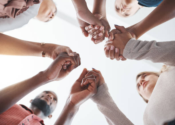 istock Community, holding hands or psychology support diversity in mental health workshop, mind or therapy. Zoom on low angle men, women or people in friends trust circle in hope, motivation or anxiety help 1446091734