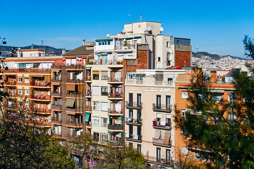 Residental building in Barcelona, mountains on the horizon, blue sky, sunny day, November 2022