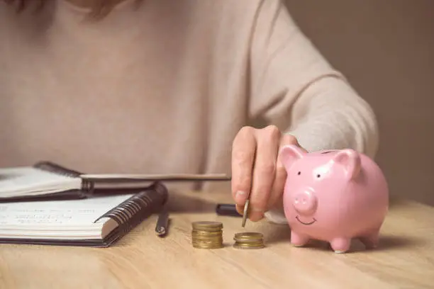 Photo of The girl puts her savings in a piggy bank.