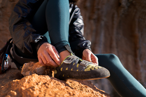 A young girl puts on special climbing shoes on her legs before climbing outdoor training, hands and feet close-up. A woman leads an active lifestyle, is involved in mountaineering and rock climbing.