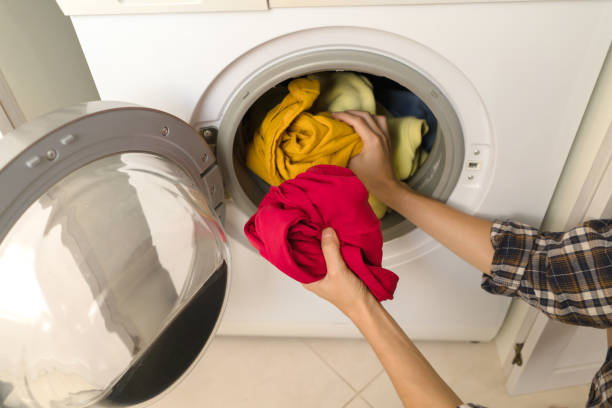 istock Woman puts bright clothes into a washing machine. 1446095882