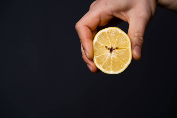 istock Man holds a lemon in his hand on the dark background. 1446097399