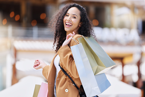 Shopping, happy and portrait of customer with bag after shopping spree buying retail fashion product on store discount. Sales, smile and young black woman at luxury shopping mall to purchase clothes