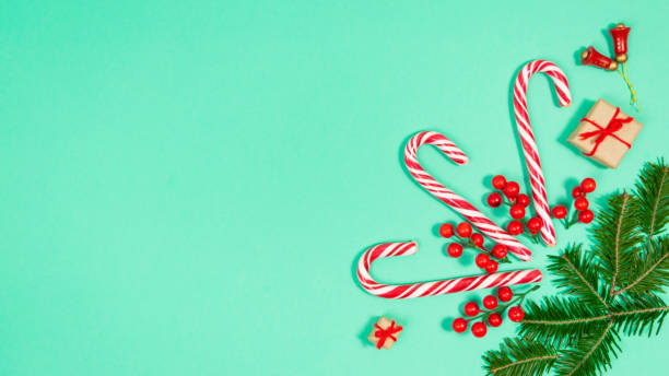 istock Candy canes and fir branches are decorated with red berries and small gift boxes. T 1446098983