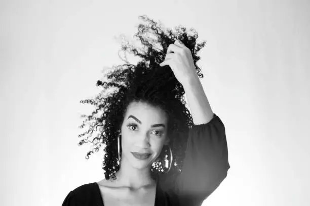 Photo of Black and white portrait of a young woman, messing with her hair.