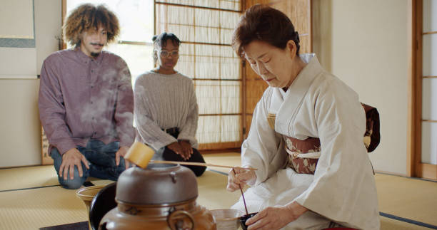 istock Attentive Guests Watching Hostess Spoon Matcha From Caddy Into Bowl at Traditional Tea Ceremony 1446100657