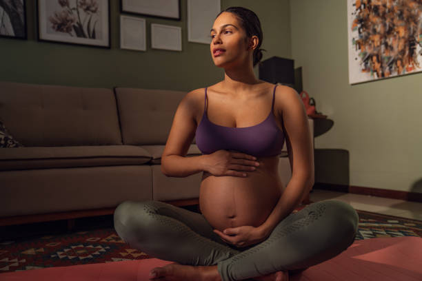 Young  expectant mother doing yoga at home stock photo