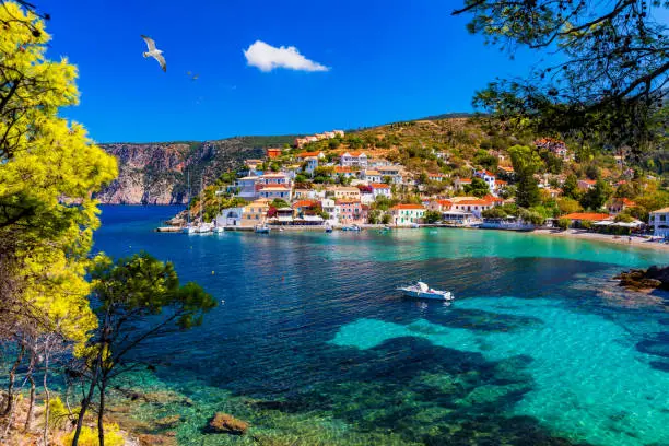 Photo of Turquoise colored bay in Mediterranean sea with beautiful colorful houses in Assos village in Kefalonia, Greece. Town of Assos with colorful houses on the mediterranean sea, Greece.