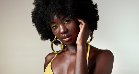 Black woman, face and makeup with skincare beauty and cosmetics against grey backdrop. Model, hand and hair, show afro, skin wellness and health in portrait against studio background in Los Angeles