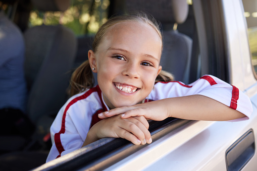 Happy, little girl and portrait smile for road trip in relax after soccer match in the car. Excited female teenager smiling in happiness for sports vacation, travel or training for football game