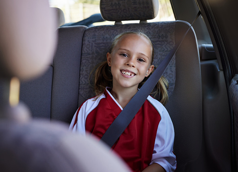 Soccer, travel and girl in a car with a happy, excited and big smile for a sports training match exercise for kids. Road, safety and young child traveling in a vehicle to a weekend football trip