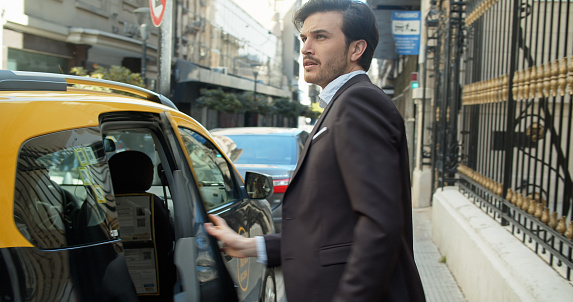 Two young Argentinian businessmen on the street of Buenos Aires getting out of a taxi.