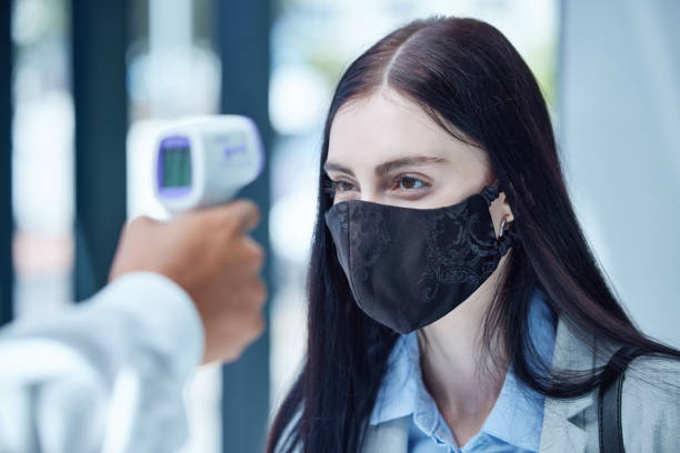 doctor, covid and thermometer for healthcare scan to test patient temperature or check for fever or symptoms. businesswoman with corona mask in exam, scanning face with infrared scanner at the office - telephone doctor medical exam healthcare and medicine imagens e fotografias de stock