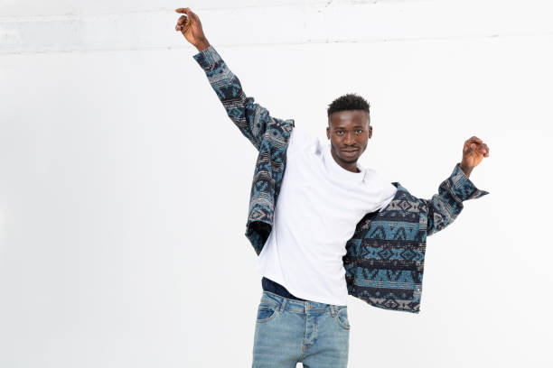 istock Young black man smiling while putting on his shirt. 1446115635