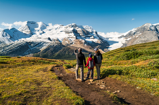 Family with one child looks at Mount Athabasca and Athabasca Glacier at Wilcox Pass, in the Canadian Rockies, Jasper National Park, Alberta, Canada.
