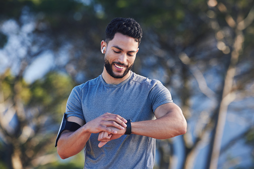 A runner with fitness smartwatch, app and check running time for health tracking tech on nature run. Sports athlete doing workout practice for cardio wellness, physical fitness and marathon training