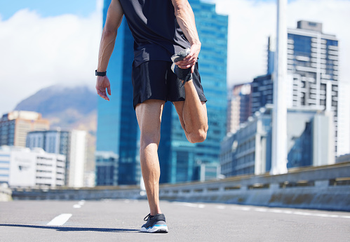 Man, stretching legs and back view in city, street or urban road outdoors. Fitness, health and male athlete stretch or warm up before exercise, running or training outside for marathon run in town.